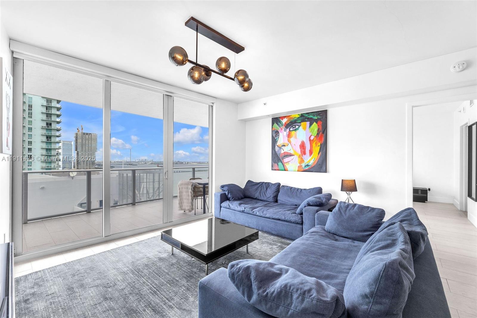 A living room features a blue sectional sofa, a coffee table, and a balcony view — 488 NE 18th St # 4311, Miami FL 33132, MIAMI, FL