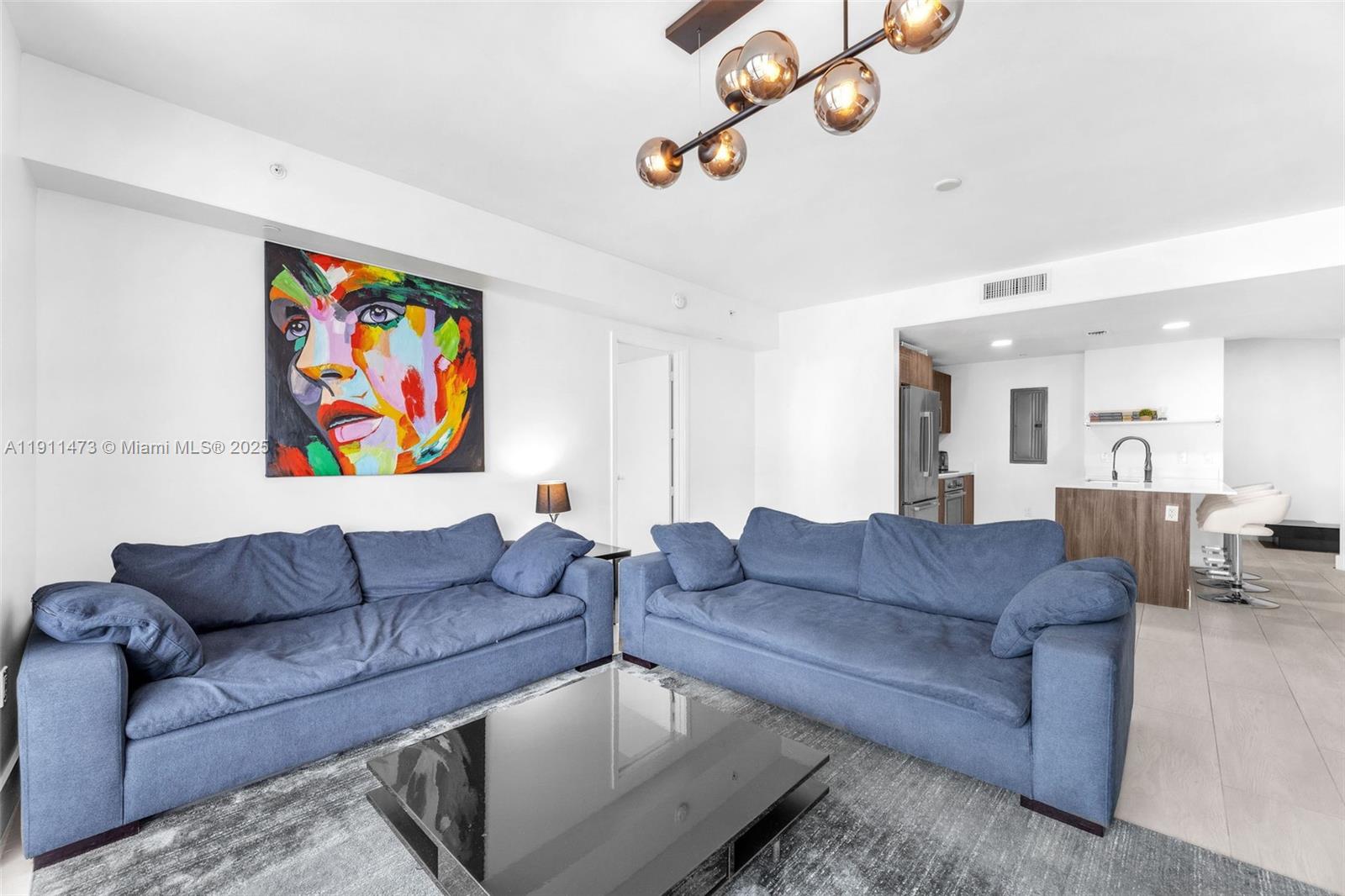 A living room features two blue sofas, a black coffee table, and colorful wall art — 488 NE 18th St # 4311, Miami FL 33132, MIAMI, FL