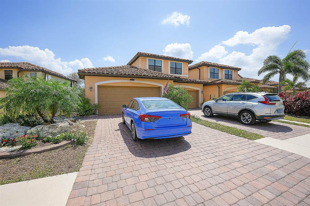 A two-story house with a tile roof, a paved driveway, and two parked cars — 20071 RAGAZZA CIRCLE UNIT 101, VENICE, FL