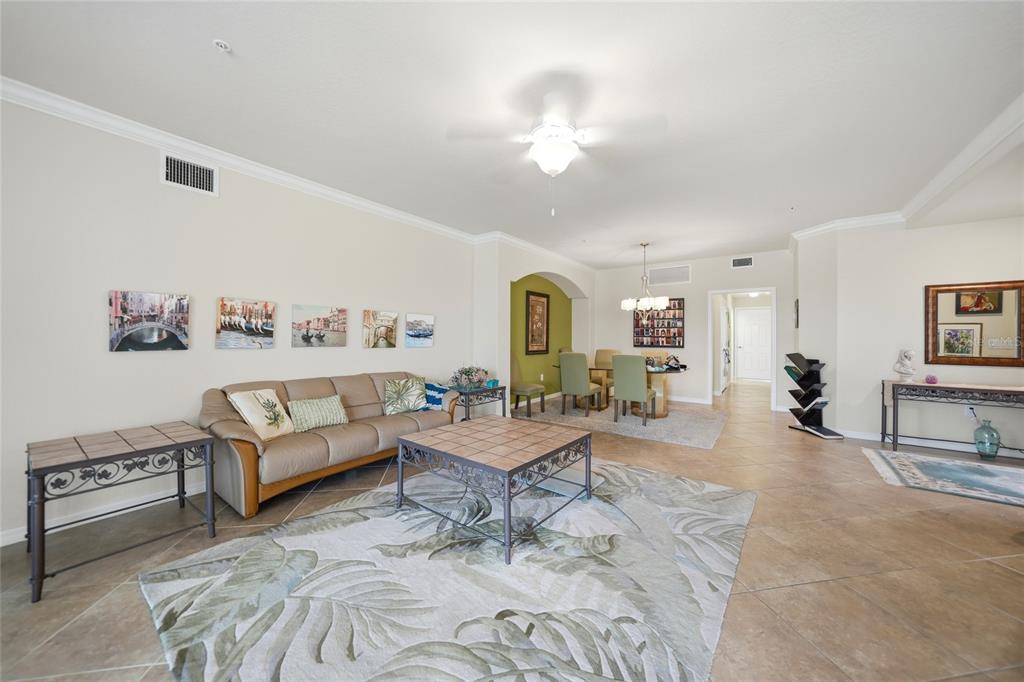 A living room with tile floors, a beige sofa, and a dining area in the background — 20071 RAGAZZA CIRCLE UNIT 101, VENICE, FL