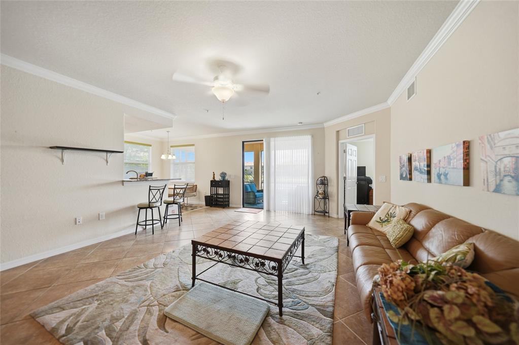 A living room with tile floors, a leather sofa, a coffee table, and a breakfast bar — 20071 RAGAZZA CIRCLE UNIT 101, VENICE, FL