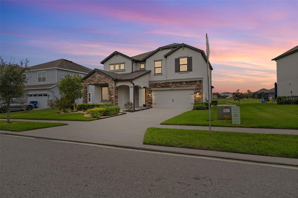 A two-story suburban house with a stone facade, a two-car garage, and a concrete driveway — 31046 PARROT REEF COURT, WESLEY CHAPEL, FL