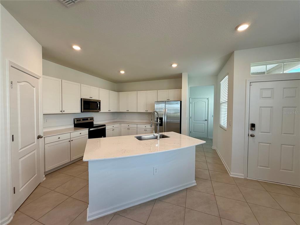 A kitchen features white cabinets, a center island with a sink, and stainless steel appliances — 268 REDBUD ROAD, PALM COAST, FL