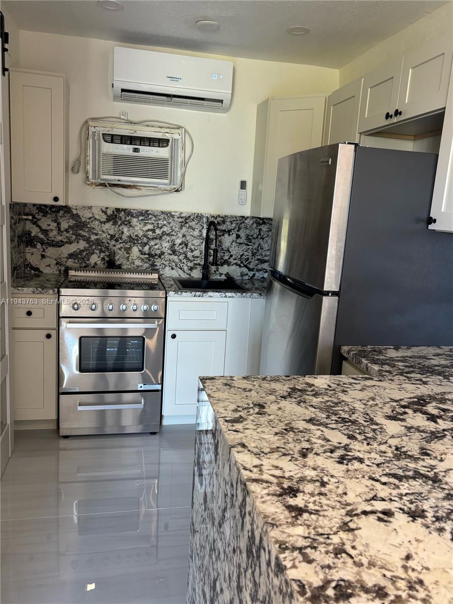 A kitchen features white cabinets, granite countertops, stainless steel appliances, and two air conditioning units — 103365 Overseas Hwy. # B, Key Largo FL 33037, KEY LARGO, FL