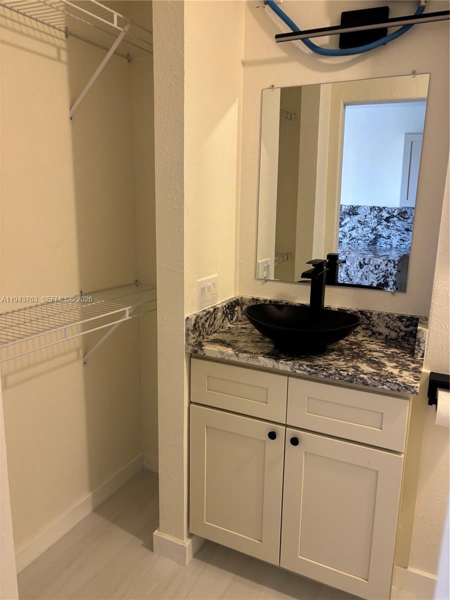 A bathroom features a black vessel sink on a granite vanity next to a closet — 103365 Overseas Hwy. # B, Key Largo FL 33037, KEY LARGO, FL