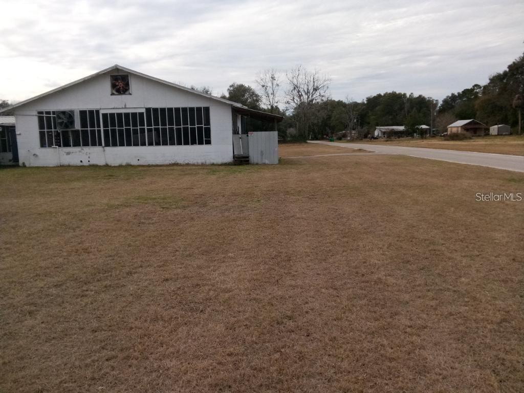 A white, single-story building with large windows sits on a grassy lot near a road — 1606 SW 4TH PLACE, CHIEFLAND, FL