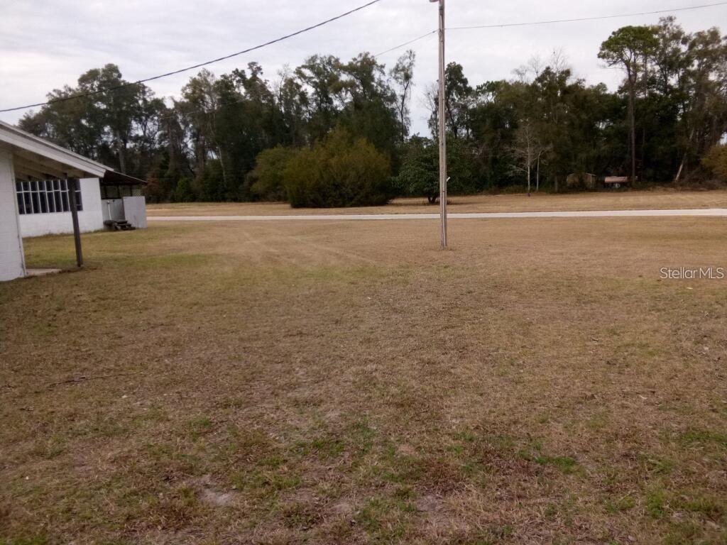 A grassy yard extends from a house toward a road and a line of trees — 1606 SW 4TH PLACE, CHIEFLAND, FL
