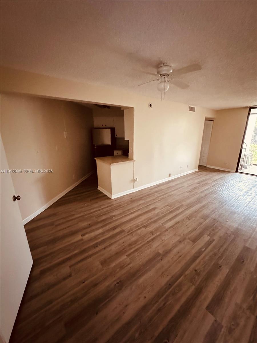 An open-concept living area features wood-look flooring, a ceiling fan, and a pass-through kitchen — 211 Lake Pointe Dr # 110, Oakland Park FL 33309, OAKLAND PARK, FL