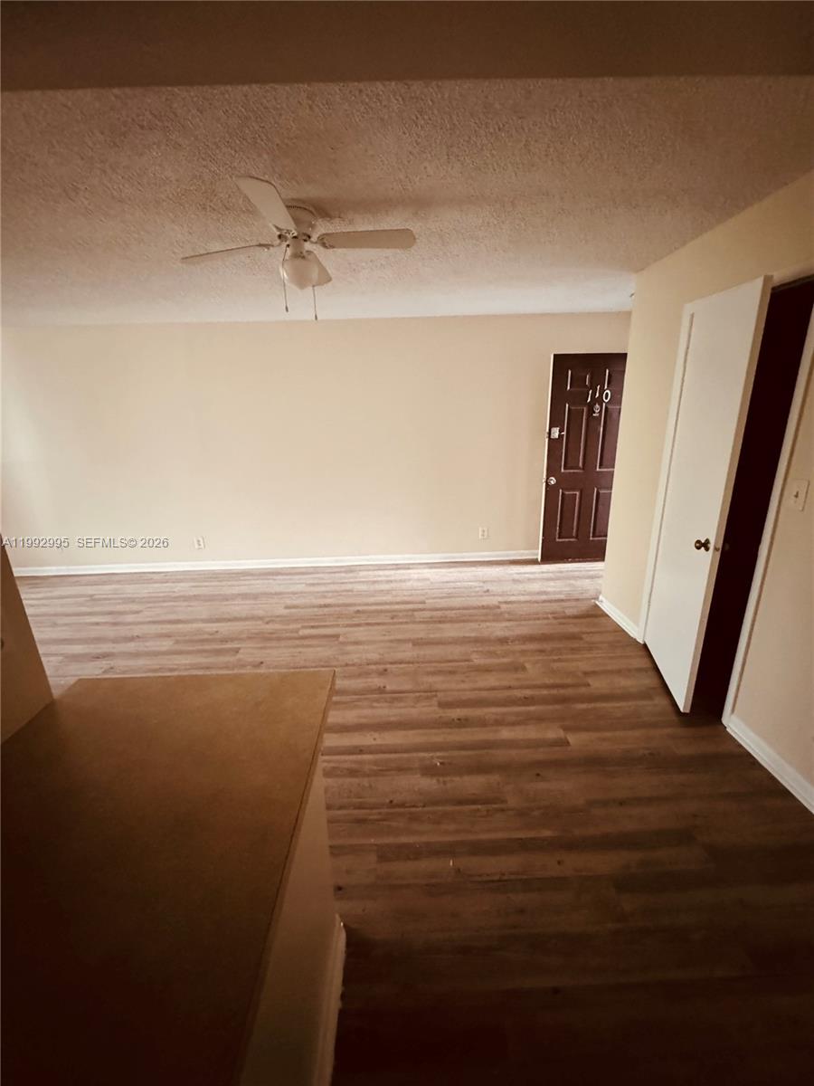 An interior view shows a living area with wood-look flooring, a ceiling fan, and doors — 211 Lake Pointe Dr # 110, Oakland Park FL 33309, OAKLAND PARK, FL