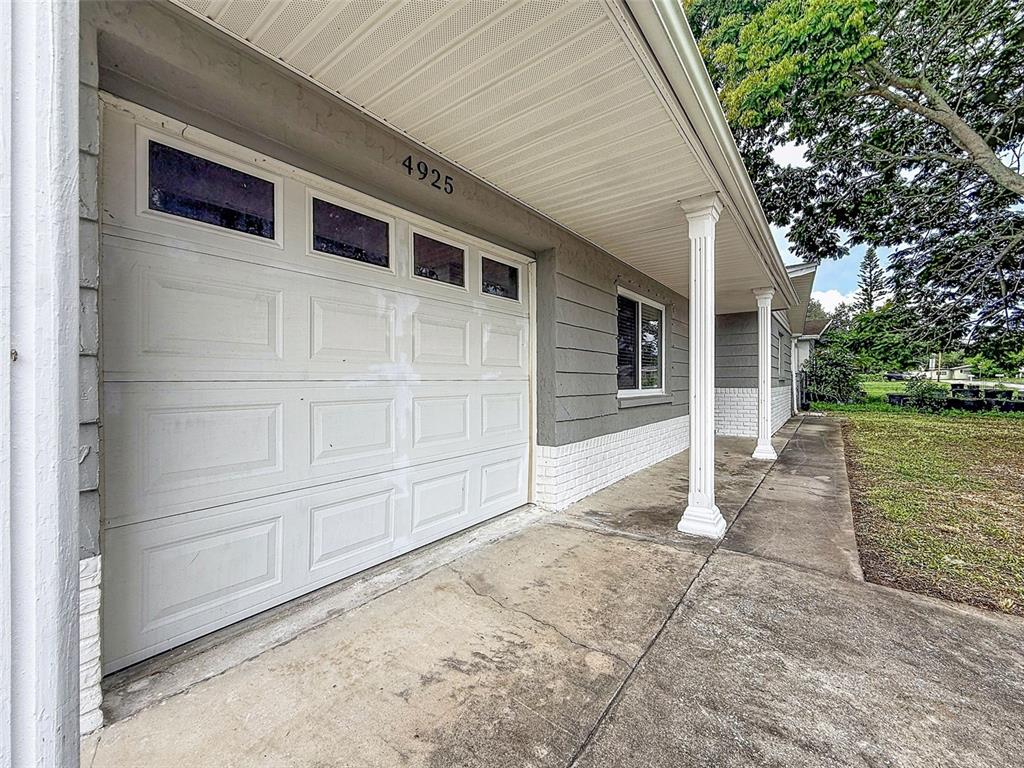 A white garage door and a covered concrete porch with columns on a house exterior — 4925 BEACON HILL DRIVE, NEW PORT RICHEY, FL