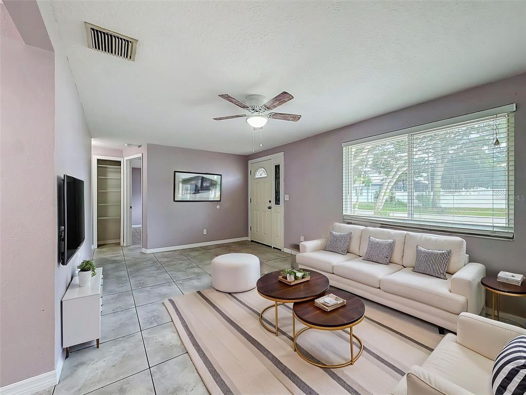 A living room features light purple walls, tile flooring, a white sofa, and a ceiling fan — 4925 BEACON HILL DRIVE, NEW PORT RICHEY, FL