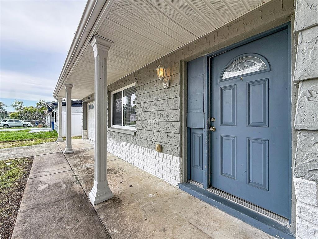 A blue front door and a covered porch with white columns on a house exterior — 4925 BEACON HILL DRIVE, NEW PORT RICHEY, FL