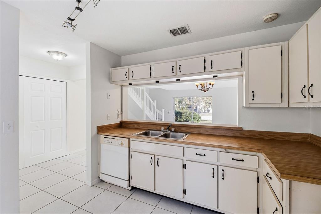 A view of a two-story tan house with a red door and a brick walkway — 6040 SCOTCHWOOD GLEN UNIT 105, ORLANDO, FL