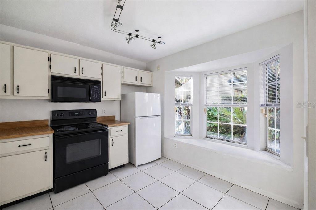 A bright living and dining area features tile floors, a staircase, and neutral-toned furniture — 6040 SCOTCHWOOD GLEN UNIT 105, ORLANDO, FL