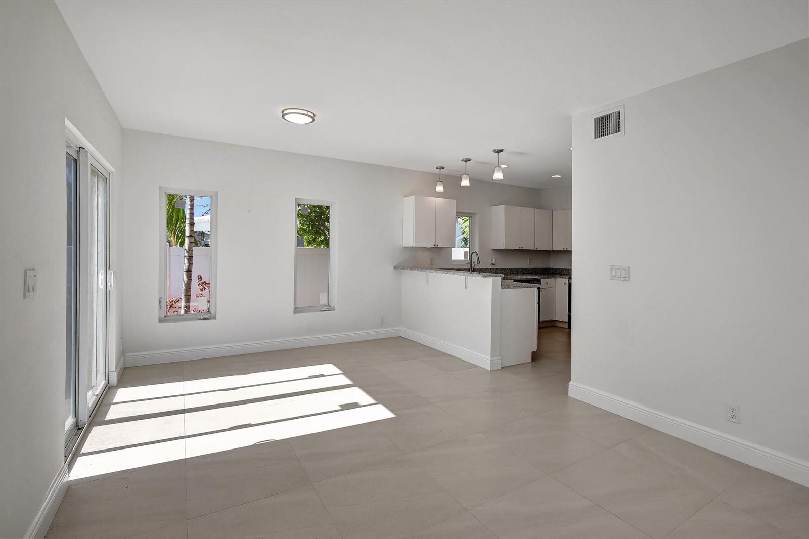 A bright, open-concept living area with white walls, tile flooring, and an adjacent kitchen — 1104 S 20th Avenue, Hollywood FL 33020, HOLLYWOOD, FL