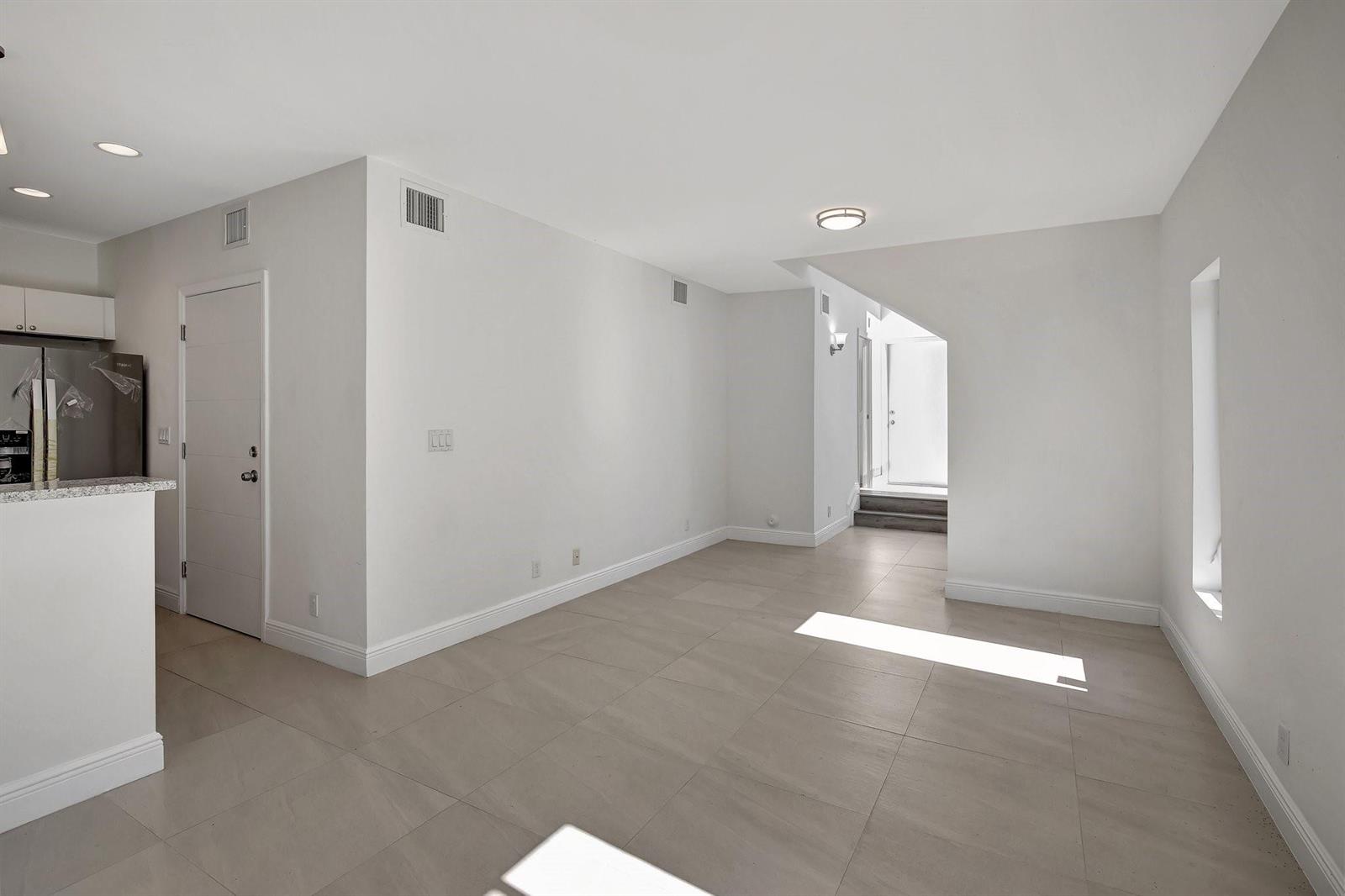 An empty room with light-colored tile flooring, white walls, and a view toward a doorway — 1104 S 20th Avenue, Hollywood FL 33020, HOLLYWOOD, FL