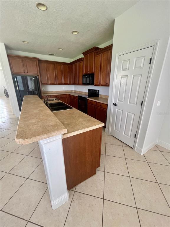 A kitchen features wood cabinets, a tan laminate countertop, and a white door — 14257 LAGOON COVE LANE, WINTER GARDEN, FL