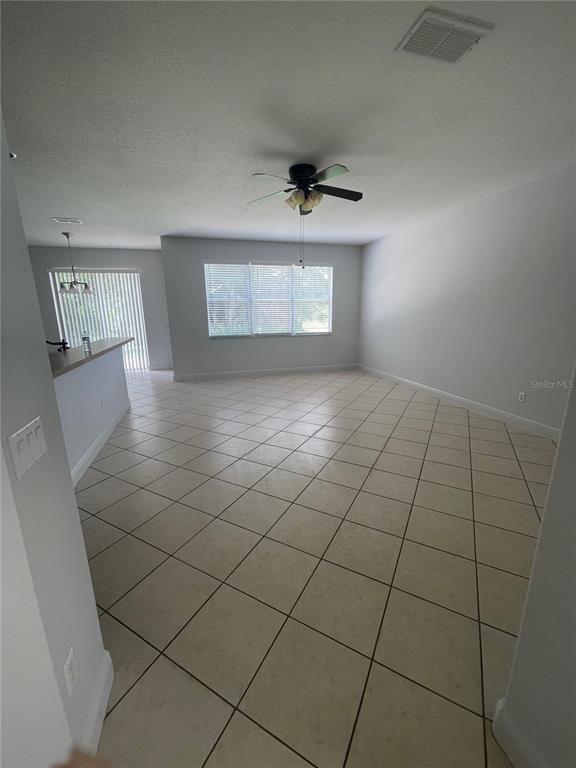 An open-concept living area features light-colored tile flooring, a ceiling fan, and a breakfast bar — 14257 LAGOON COVE LANE, WINTER GARDEN, FL