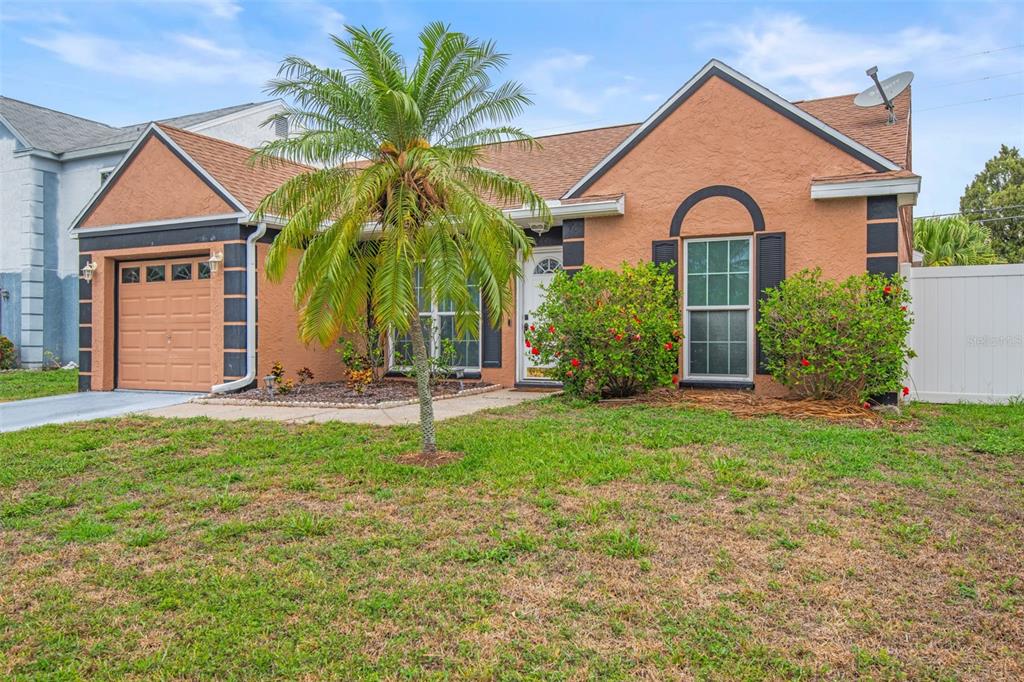 A single-story peach-colored house with a palm tree, garage, and front lawn — 7591 121ST TERRACE, LARGO, FL