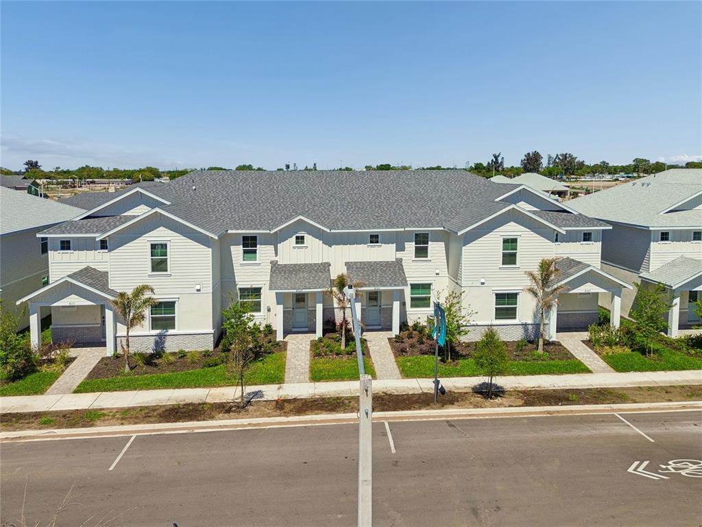 A multi-unit residential building with light-colored siding, gray shingled roofs, and paved walkways — 8111 SEAFLOWER PARKWAY, BRADENTON, FL