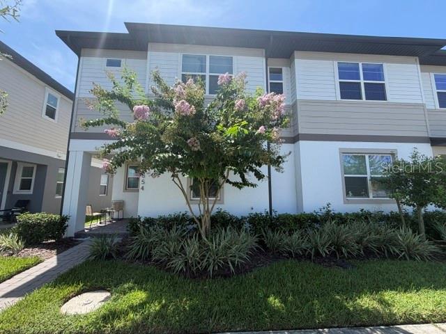 A two-story townhouse exterior features a blooming crape myrtle tree and a paved walkway — 3854 KNOTTY PINE STREET, ST CLOUD, FL