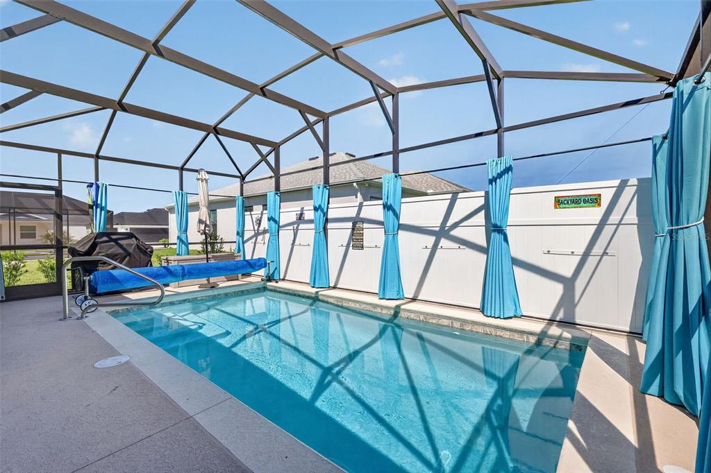 A screened-in patio features a rectangular swimming pool with a blue cover and curtains — 7478 SAVANNA DRIVE, THE VILLAGES, FL