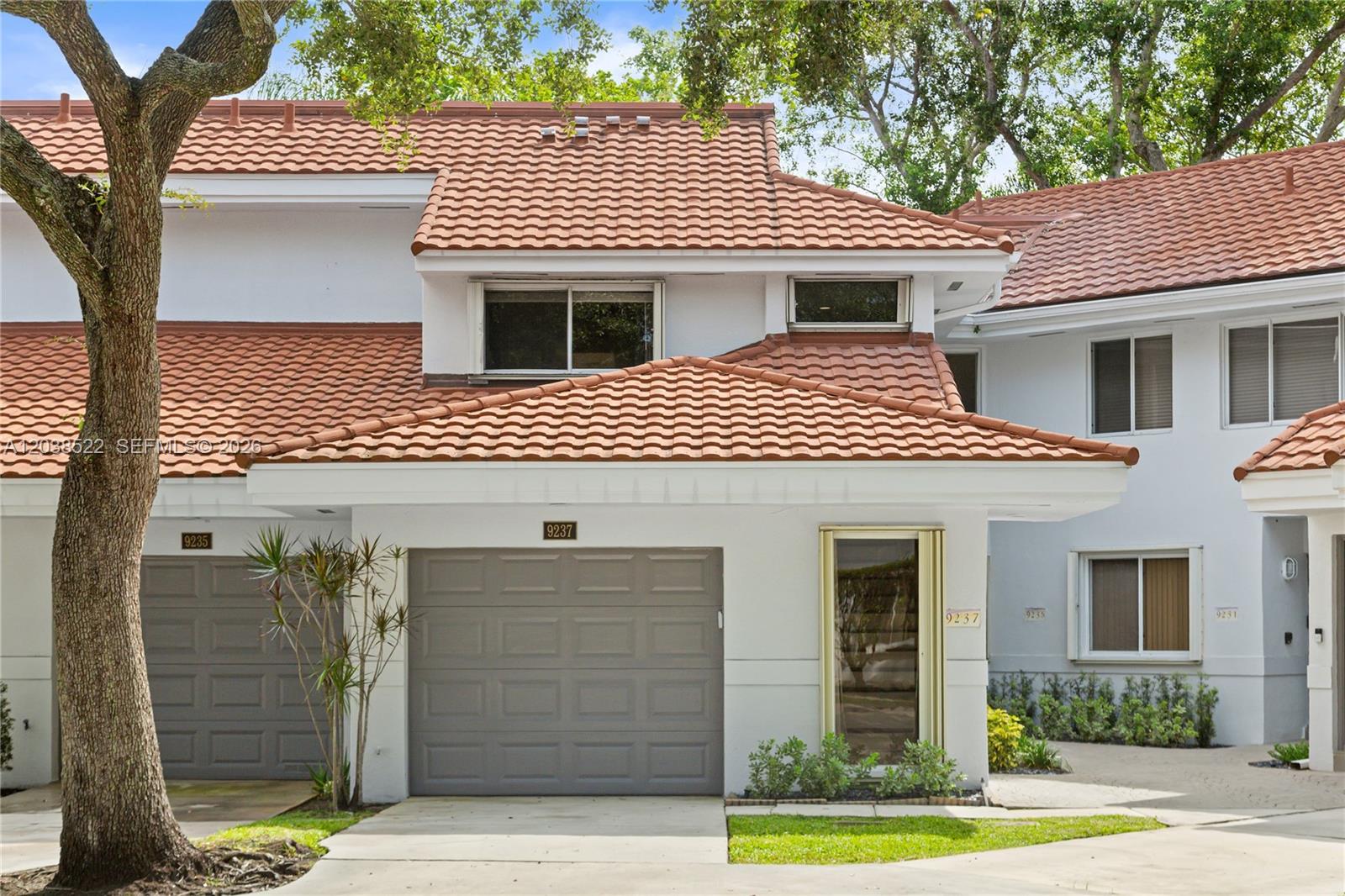 A two-story townhouse exterior features a gray garage door, white walls, and a tiled roof — 9237 NW 9th Pl # 9257, Plantation FL 33324, PLANTATION, FL