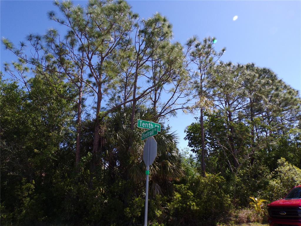 A street sign for Tenth Avenue and Pinetrail Road stands before tall pine trees — 11383 10TH AVENUE, PUNTA GORDA, FL