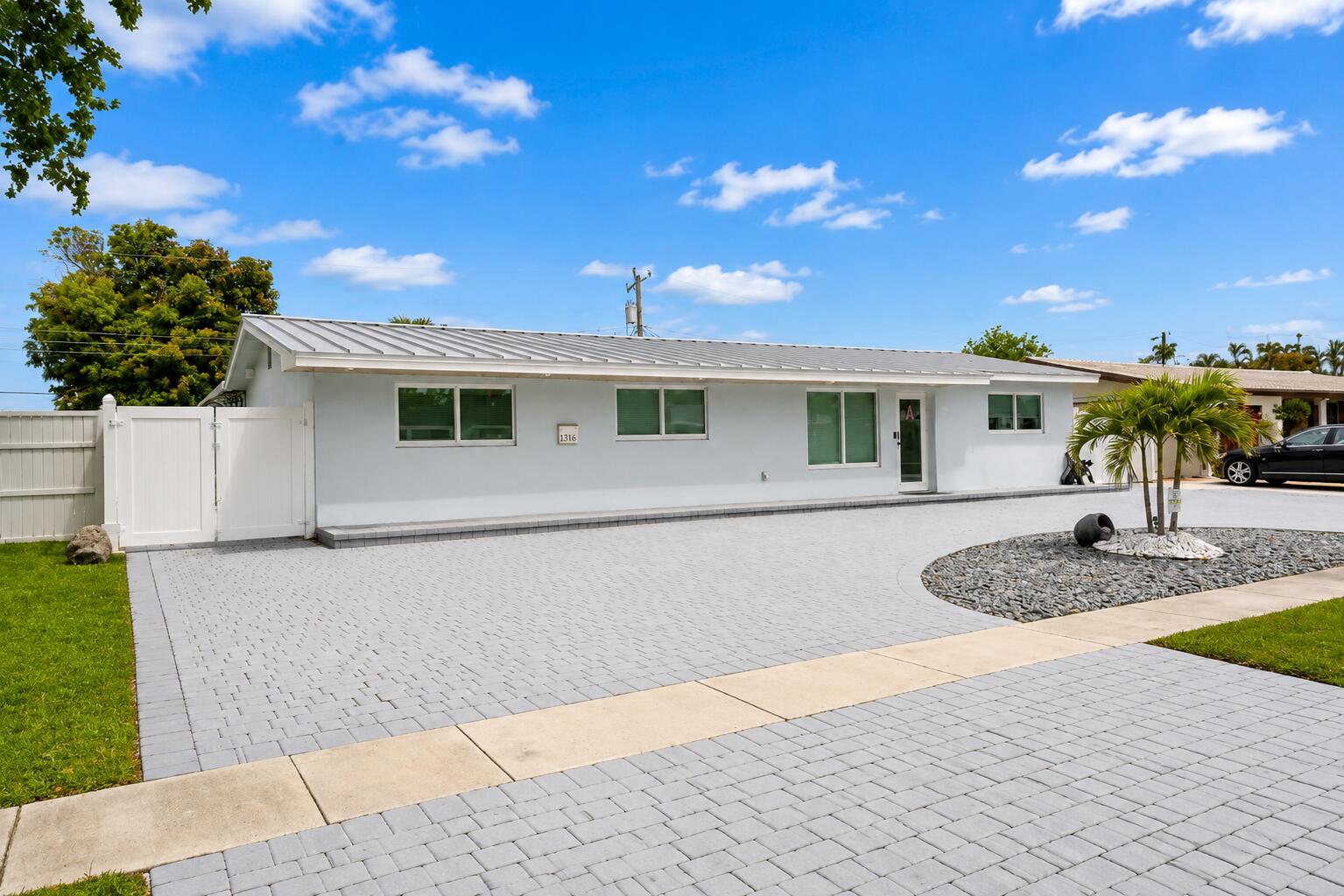 A light blue single-story house features a metal roof and a paved driveway — 1316 SE 3rd Avenue, Deerfield Beach FL 33441, DEERFIELD BEACH, FL