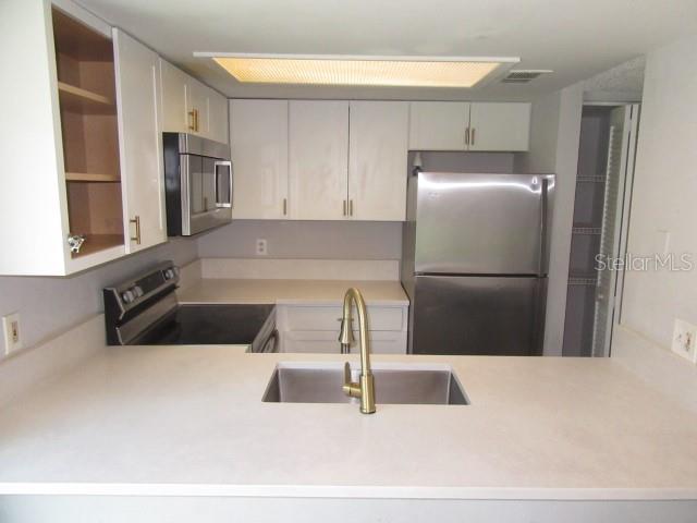 A kitchen features white cabinetry, stainless steel appliances, a sink, and a countertop — 13042 LONDONDARY PLACE, TAMPA, FL