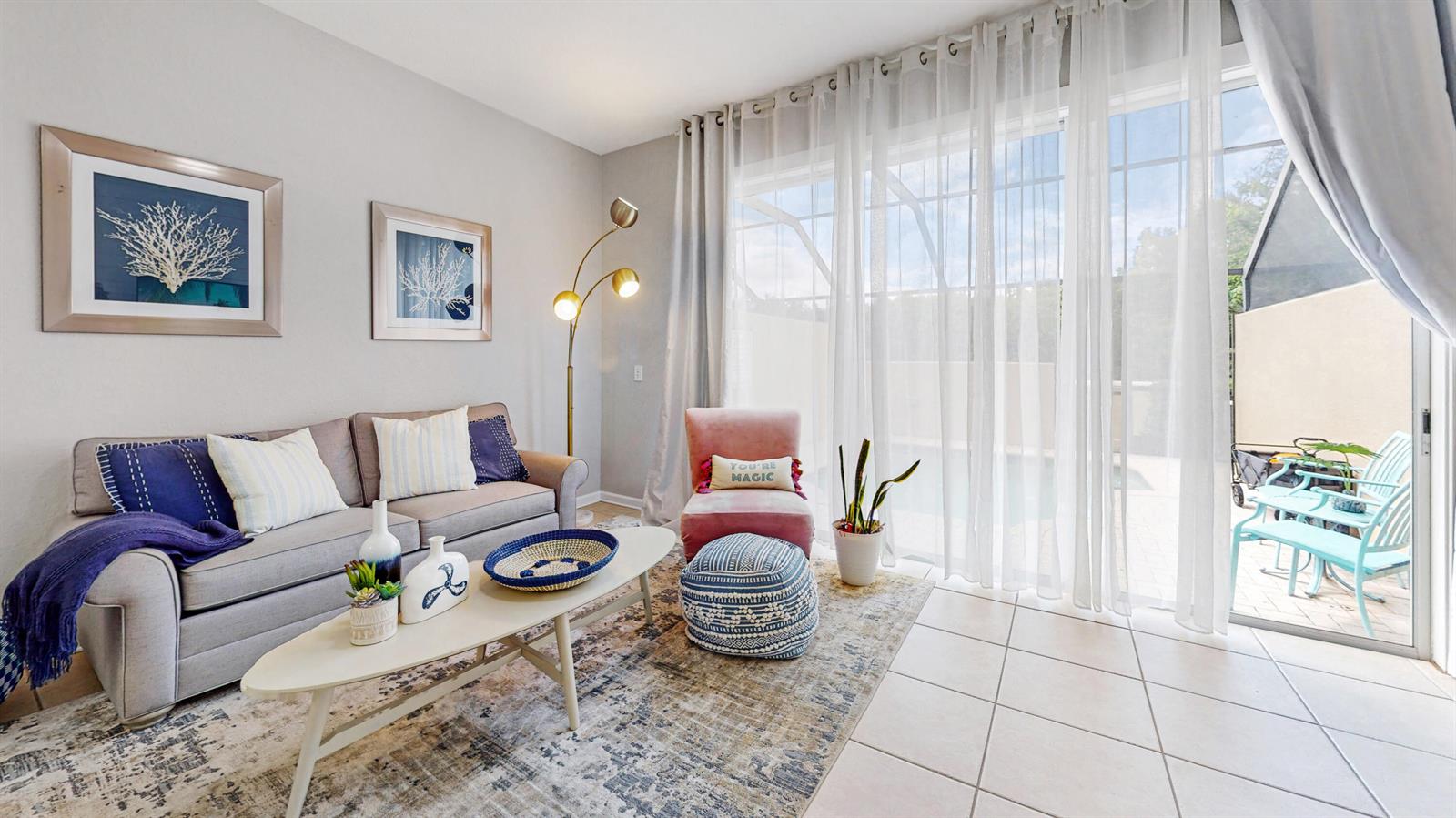 A living room features a gray sofa, a pink chair, and a sliding glass door — KISSIMMEE, FL