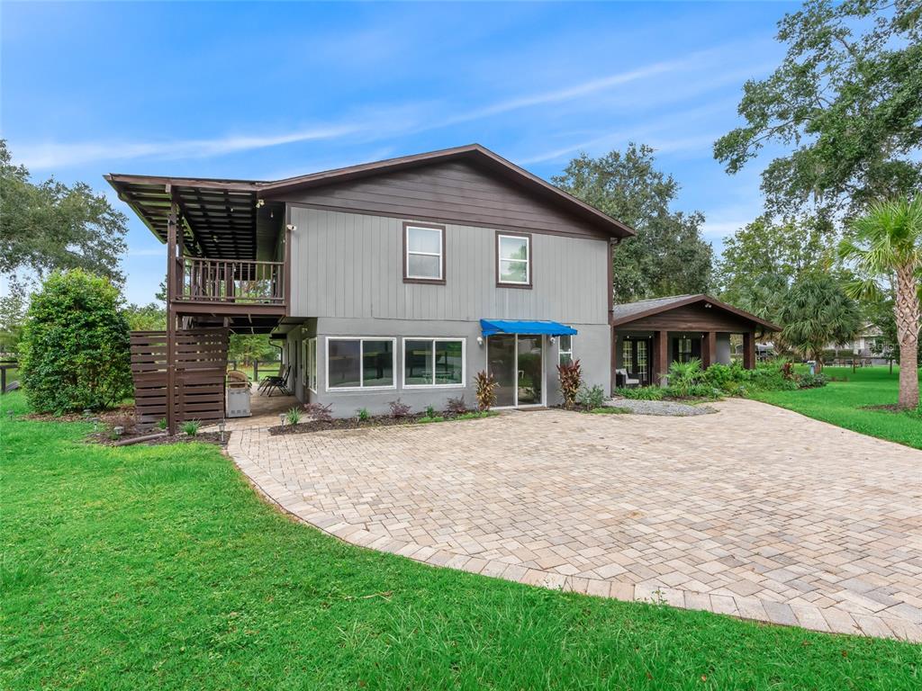 A two-story house with gray siding, a brown roof, and a large paver patio — 10291 W 40 HIGHWAY, OCALA, FL