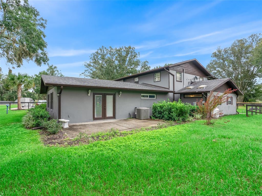The exterior of a gray two-story house features a concrete patio and green lawn — 10291 W 40 HIGHWAY, OCALA, FL