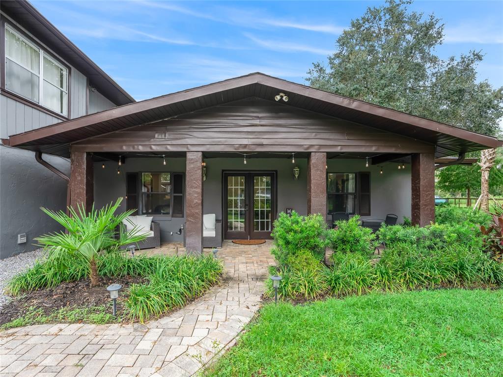 A covered front porch features a brick walkway, dark wooden columns, and French doors — 10291 W 40 HIGHWAY, OCALA, FL