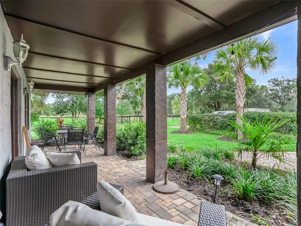 A covered patio with brick pavers, outdoor furniture, and a view of a grassy yard — 10291 W 40 HIGHWAY, OCALA, FL