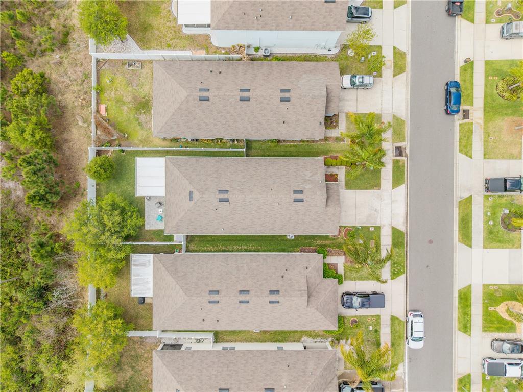 An aerial view shows a row of suburban houses with shingled roofs and backyards — 2820 TATON TRACE, NEW SMYRNA BEACH, FL