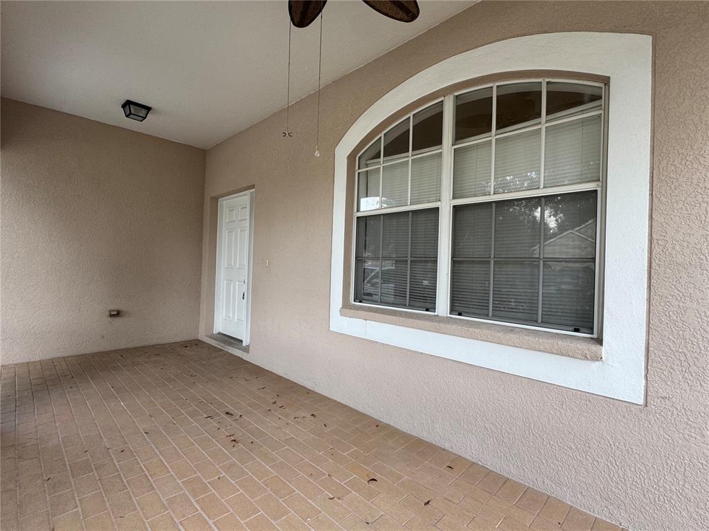 A covered patio features a tiled floor, a white door, and a large arched window — 13052 TERRACE SPRINGS DRIVE, TEMPLE TERRACE, FL