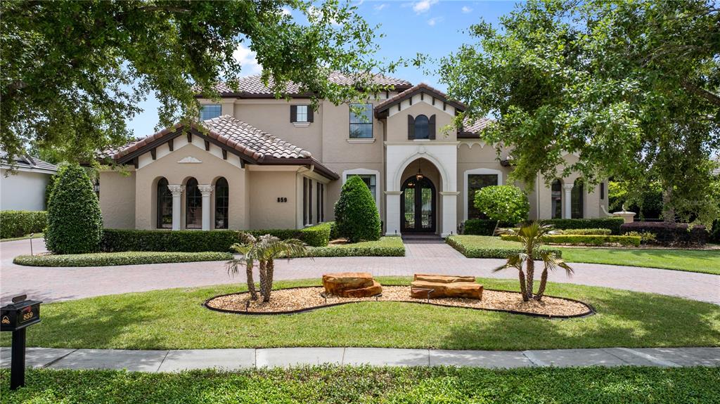A two-story stucco house with a tiled roof, arched entryway, and a circular paved driveway — 859 ISLE POINT, SANFORD, FL