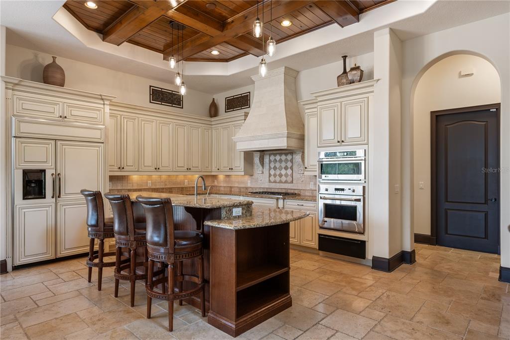 A kitchen features cream cabinets, a dark wood island with barstools, and a coffered ceiling — 859 ISLE POINT, SANFORD, FL