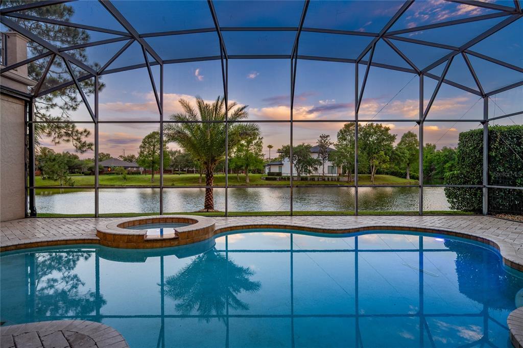 A screened-in pool and spa overlook a lake at sunset — 859 ISLE POINT, SANFORD, FL