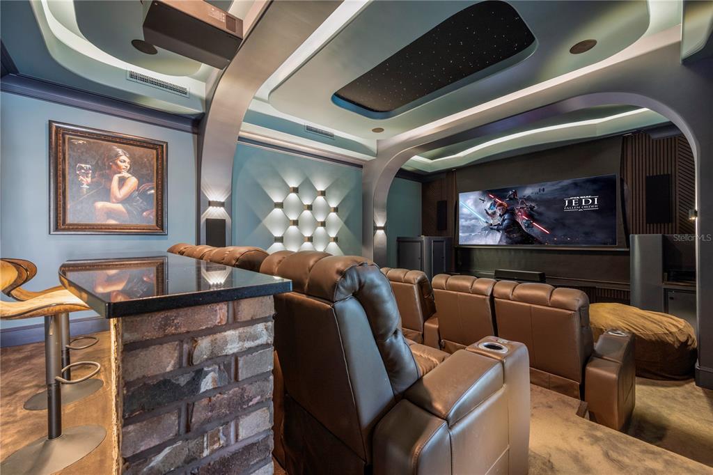 A home theater features tiered leather seating, a projector screen, and a brick-based bar area — 859 ISLE POINT, SANFORD, FL