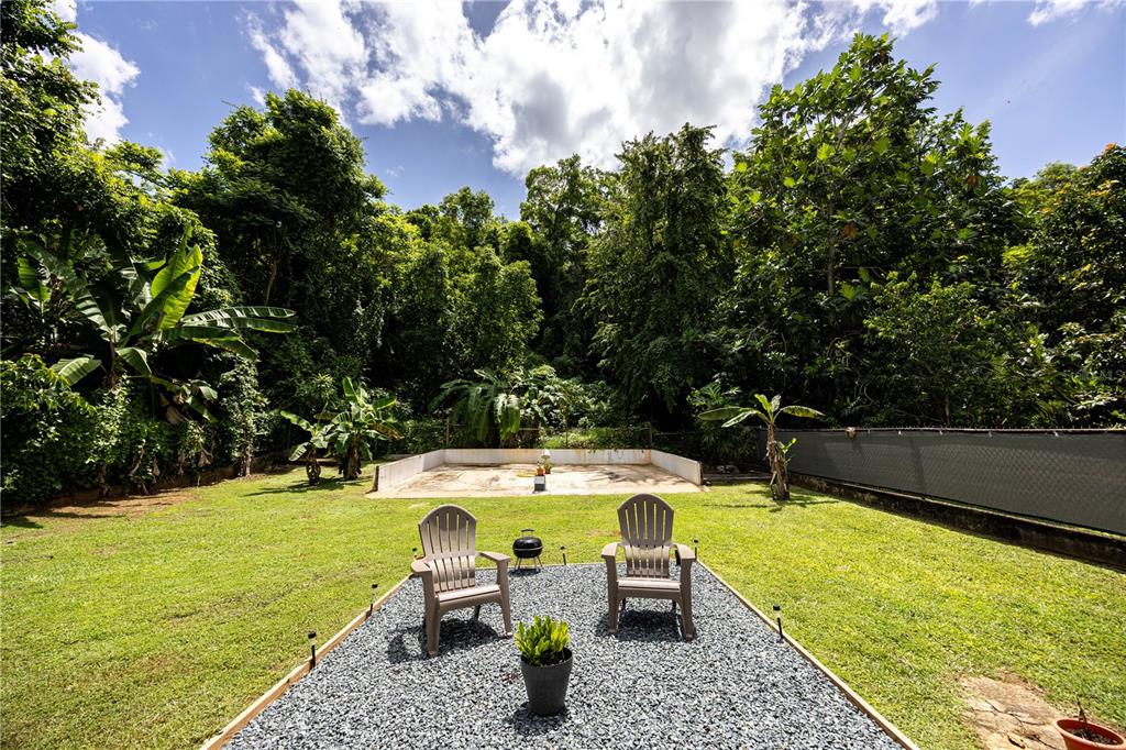 A backyard features a gravel patio with two chairs, a small grill, and a concrete slab — Bo. Tierras Nuevas COLINAS DEL NORTE UNIT BB-1, MANATI, PR