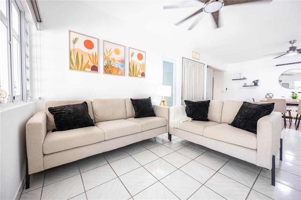 A living room features two beige sofas with black pillows and three framed wall prints — Bo. Tierras Nuevas COLINAS DEL NORTE UNIT BB-1, MANATI, PR