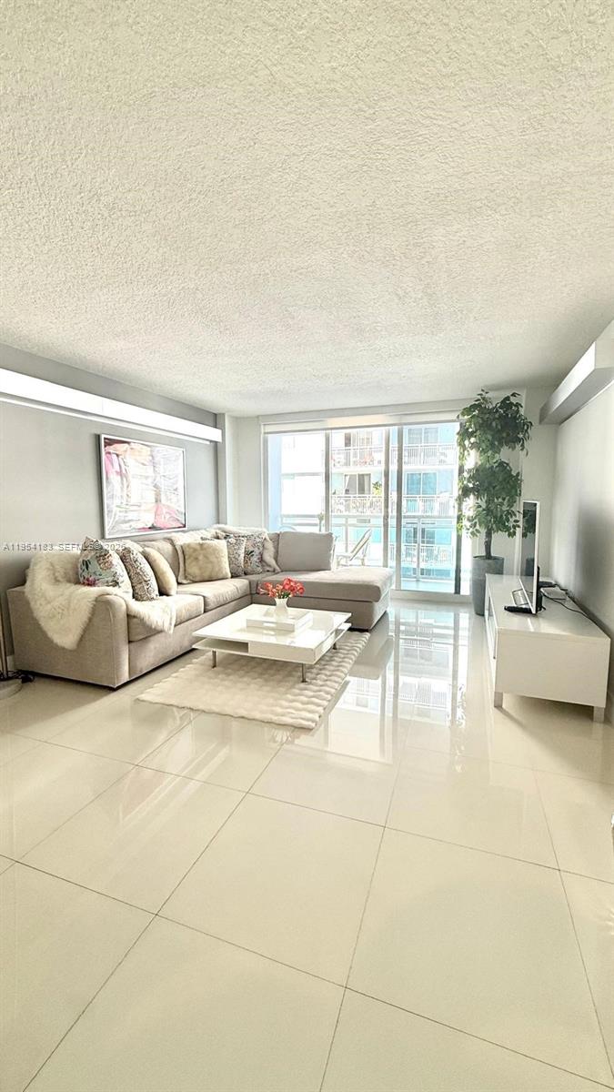 A bright living room features a sectional sofa, a white coffee table, and tile flooring — 6917 Collins Ave # 1206, Miami Beach FL 33141, MIAMI BEACH, FL