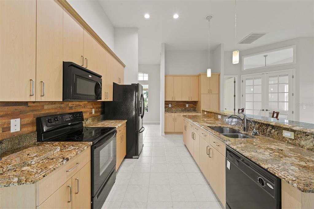 A kitchen with light wood cabinets, granite countertops, black appliances, and a tile floor — 2727 NW 45TH PLACE, CAPE CORAL, FL
