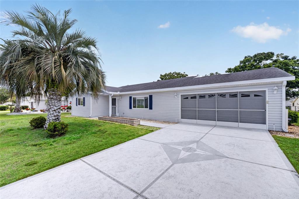 A single-story house with light gray siding, a palm tree, and a decorative concrete driveway — 9532 SE 173RD LANE, SUMMERFIELD, FL