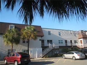 A multi-story apartment building with a parking lot and palm trees in the foreground — 9105 TUDOR DRIVE UNIT 203, TAMPA, FL