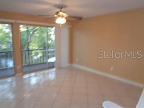 A room with light-colored tile flooring, a ceiling fan, and a sliding glass door — 9105 TUDOR DRIVE UNIT 203, TAMPA, FL