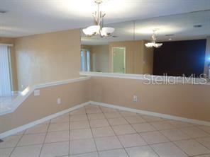 A dining area with tiled floors, a half-wall, and a large mirror on the wall — 9105 TUDOR DRIVE UNIT 203, TAMPA, FL