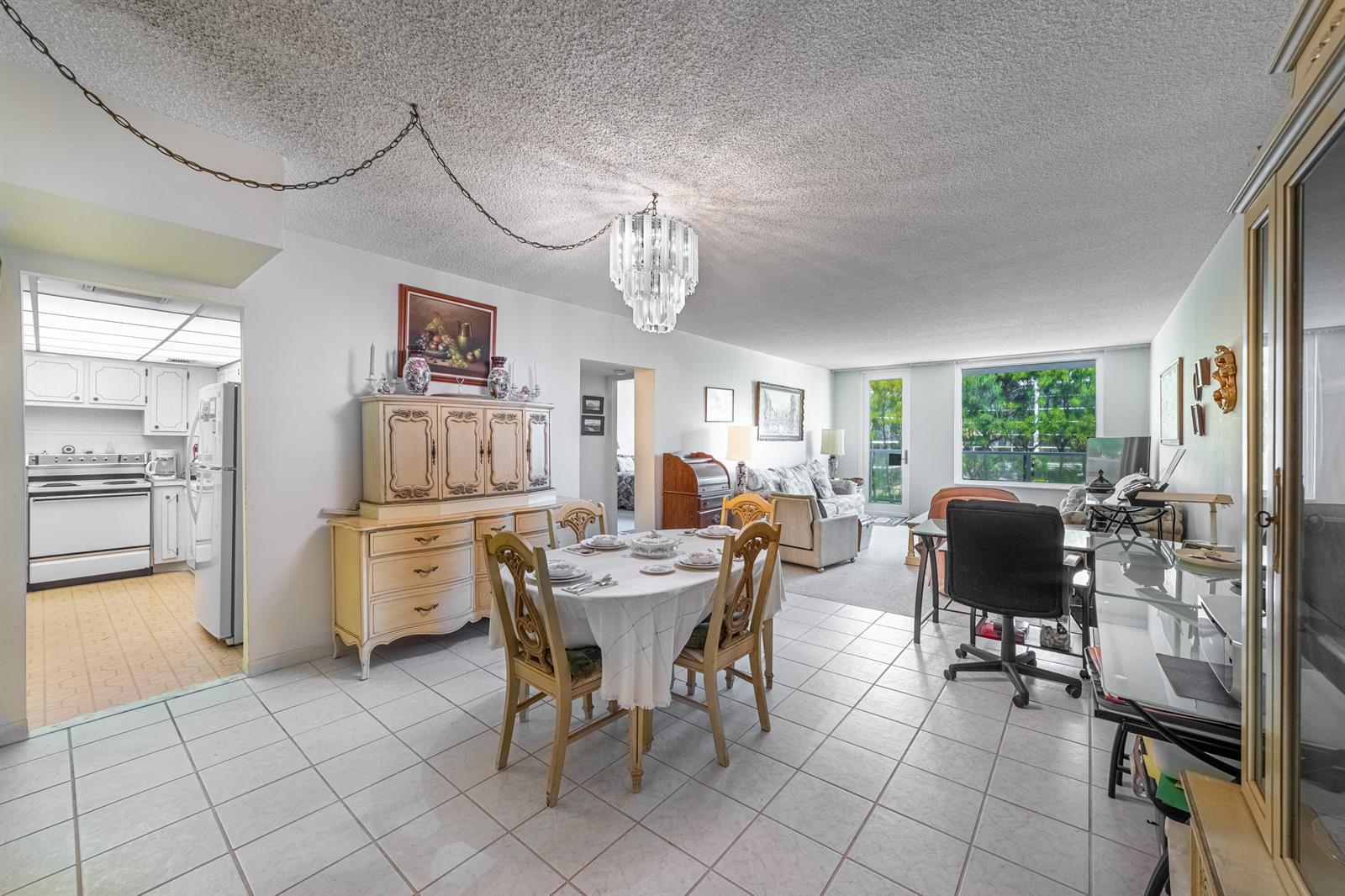A dining area with a chandelier and hutch opens into a kitchen and living room — 3450 S Ocean Boulevard # 206, Palm Beach FL 33480, PALM BEACH, FL